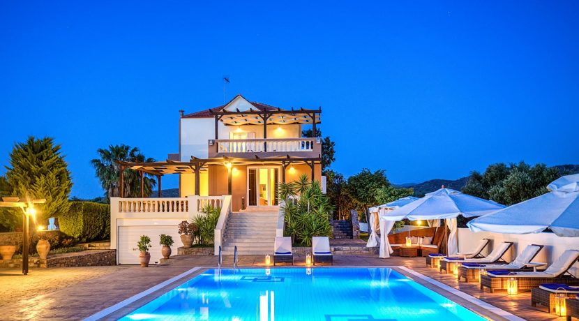 וילה יוקרתית בכרתים עם בריכה מוארת בלילה, פרויקט מגורים מוגמר עם נוף פתוח