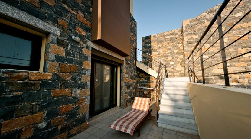 חצר פנימית בבית אבן בכרתים לאחר סיום בנייה, מעבר מרוצף בין קירות אבן מודרניים